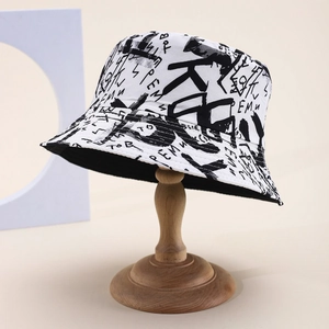 Detail of white cotton bucket hat featuring black graffiti letters on a wooden stand