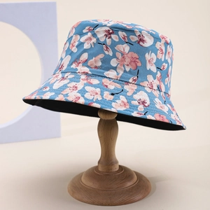 Detail of floral bucket hat in sky blue with pink flowers on a wooden stand