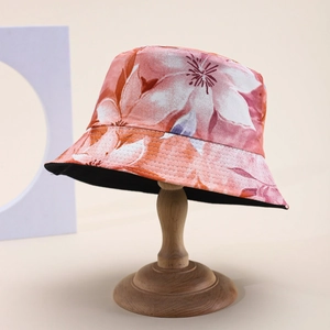 Artistic bucket hat with vibrant floral prints and black lining on a wooden display stand