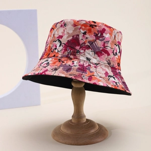 Detail of floral bucket hat with vibrant abstract patterns on a wooden display stand