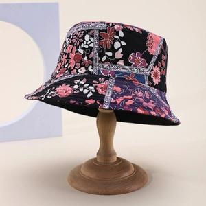 Detail shot of a black bohemian bucket hat with vibrant floral patterns on a wooden stand