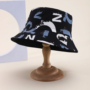 Detail view of cotton canvas bucket hat with graffiti letter patterns on a wooden stand
