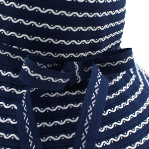 Detail of navy straw hat featuring white wavy stripes and a stylish matching bow accent