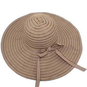 Detail of wide brim straw sun hat featuring brown stripes and a matching bow tie