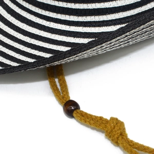 Detail of black and white striped straw hat with adjustable yellow woven cord