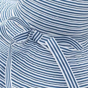 Close-up of blue and white striped woven sun hat fabric with a stylish bow detail