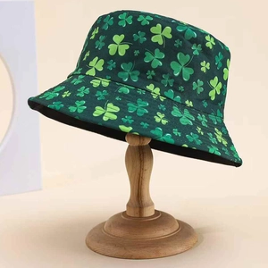 Double-sided sun hat with green leaf clover print on a wooden stand minimalist background