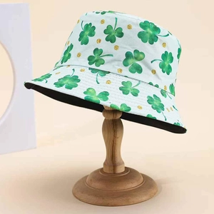 Reversible bucket hat with green leaf print and gold glitter on wooden stand