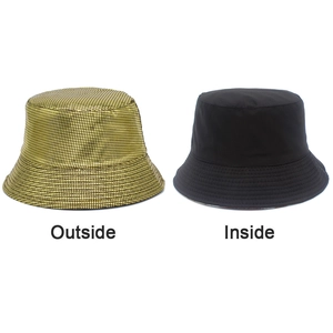 Detail view of reversible bucket hat showing metallic gold texture and plain black fabric side