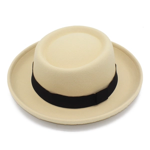 Dettaglio di un cappello di feltro beige con nastro di canneté nero su sfondo bianco