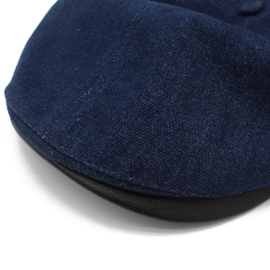 Detailed close-up of dark blue denim fabric with black leather brim and stitching