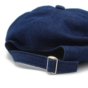 Navy blue denim newsboy hat with adjustable silver metal buckle on a minimalist back view