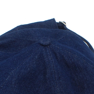 Detail of dark blue denim baker boy hat with metal buckle and twill fabric texture