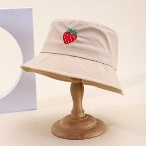Cappello a secchiello in cotone beige con ricamo a fragola su supporto di legno