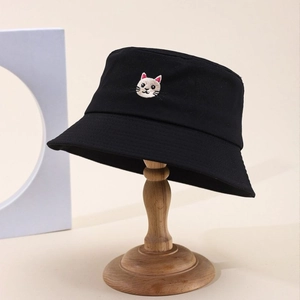 Detailed view of a black cotton bucket hat with cat embroidery on a wooden stand