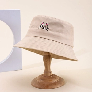 Beige cotton bucket hat featuring a cute cat embroidery on a wooden stand