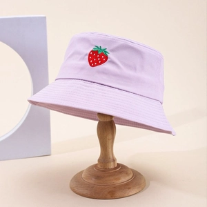 Cappello a secchiello in tela lilla con ricamo a fragola esposto su supporto in legno