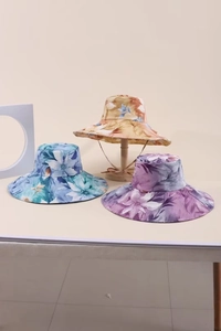 Dettaglio di cappelli da sole floreali con tesa larga e laccetti antivento regolabili