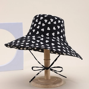 Detail of black sun hat with white heart pattern and matching windproof bow tie