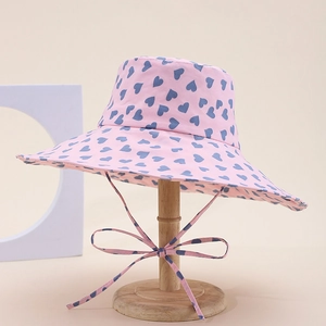 Pink fisherman hat with blue heart patterns and a stylish chin strap bow detail