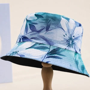 Stylish bucket hat with blue tropical floral print and black lining on wooden display