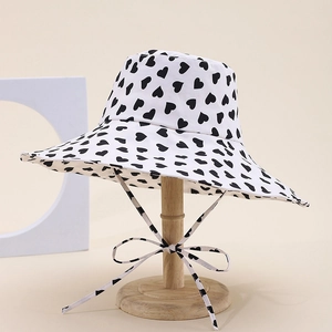 White wide-brim sun hat with black heart pattern and matching bow strap detail