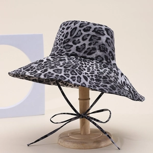 Detailed view of leopard print sun hat with stylish chin strap on a wooden stand