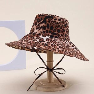 Detailed view of leopard print sun hat with wavy brim and tie strap on a wooden stand