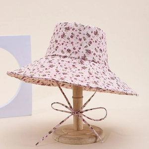 Detailed view of a pink floral sun hat with ribbon ties on a wooden display stand