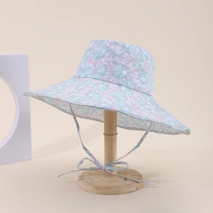 Dettaglio cappello sole bimbi con stampa tulipani e laccetto su supporto di legno