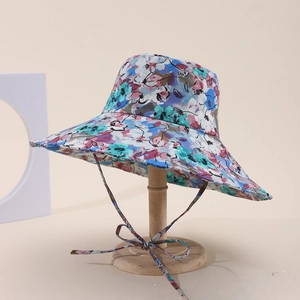 Dettaglio di cappello da sole a fiori a tesa larga con sottogola su supporto di legno