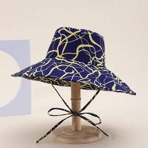 Close-up of a wide-brim dark blue sun hat with yellow abstract print and adjustable wind rope
