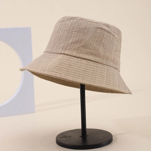 Elegant beige bucket hat with bubble texture and sparkling rhinestones on metal stand