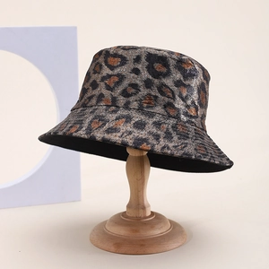 Détail d'un chapeau bob léopard à l'aspect métallique présenté sur un support bois