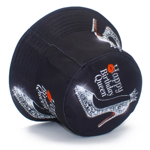 Close-up of black cotton bucket hat with Happy Birthday Queen text and silver high heels