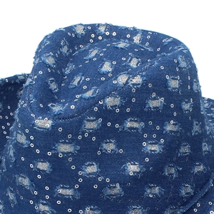 Detail of blue denim cowboy hat with distressed holes, silver glitter, and shiny sequins
