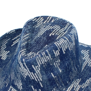 Detailed close-up of dark blue denim hat surface featuring vertical rows of silver sequins