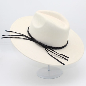 Close-up of cream wide-brim fedora hat with black braided leather band and tassel detail