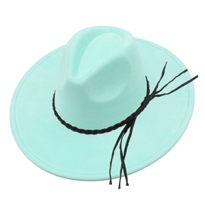 Detail of mint green fedora hat featuring black braided band and fringe accents