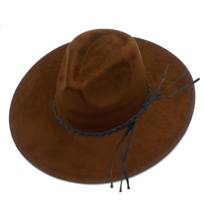 Close-up of a brown suede fedora featuring a black braided leather band and long tassels