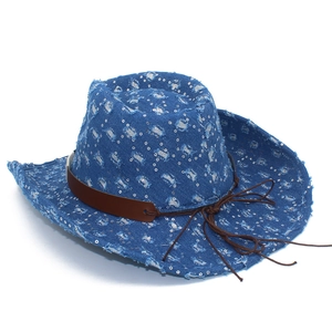 Détail d'un chapeau de cowboy en denim bleu avec paillettes argentées et bords effilochés