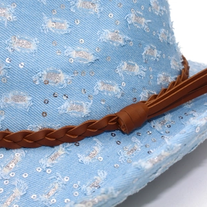 Close-up of blue denim fedora with silver sequins, woven leather band and frayed edges