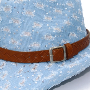 Détail d'un chapeau de cowboy en denim délavé avec paillettes argentées et lanière en cuir