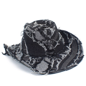 Detail of distressed black denim cowboy hat featuring frayed edges and shredded tassel trim