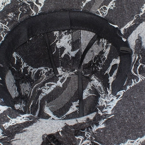 Detailed view of the inner lining and black sweatband of a distressed denim fedora hat