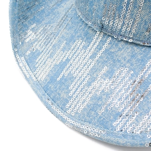 Dettaglio di paillettes argento su cappello in denim azzurro con texture a onde