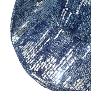 Dettaglio ravvicinato di paillettes argentate su tessuto denim blu scuro di un cappello
