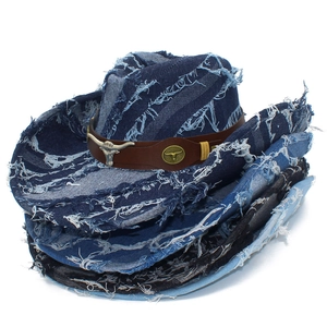 Détail d'un chapeau de cowboy en denim usé avec boucle tête de taureau et bords effilochés