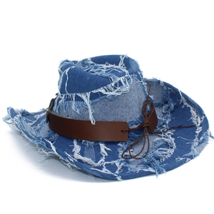 Détail d'un chapeau de cowboy en denim délavé avec bords usés et ceinture en cuir