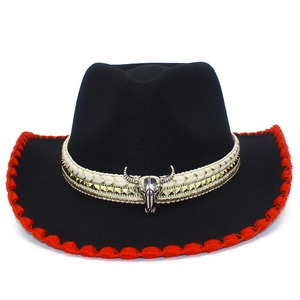 Detail of black felt cowboy hat featuring red stitched brim and silver bull skull ornament